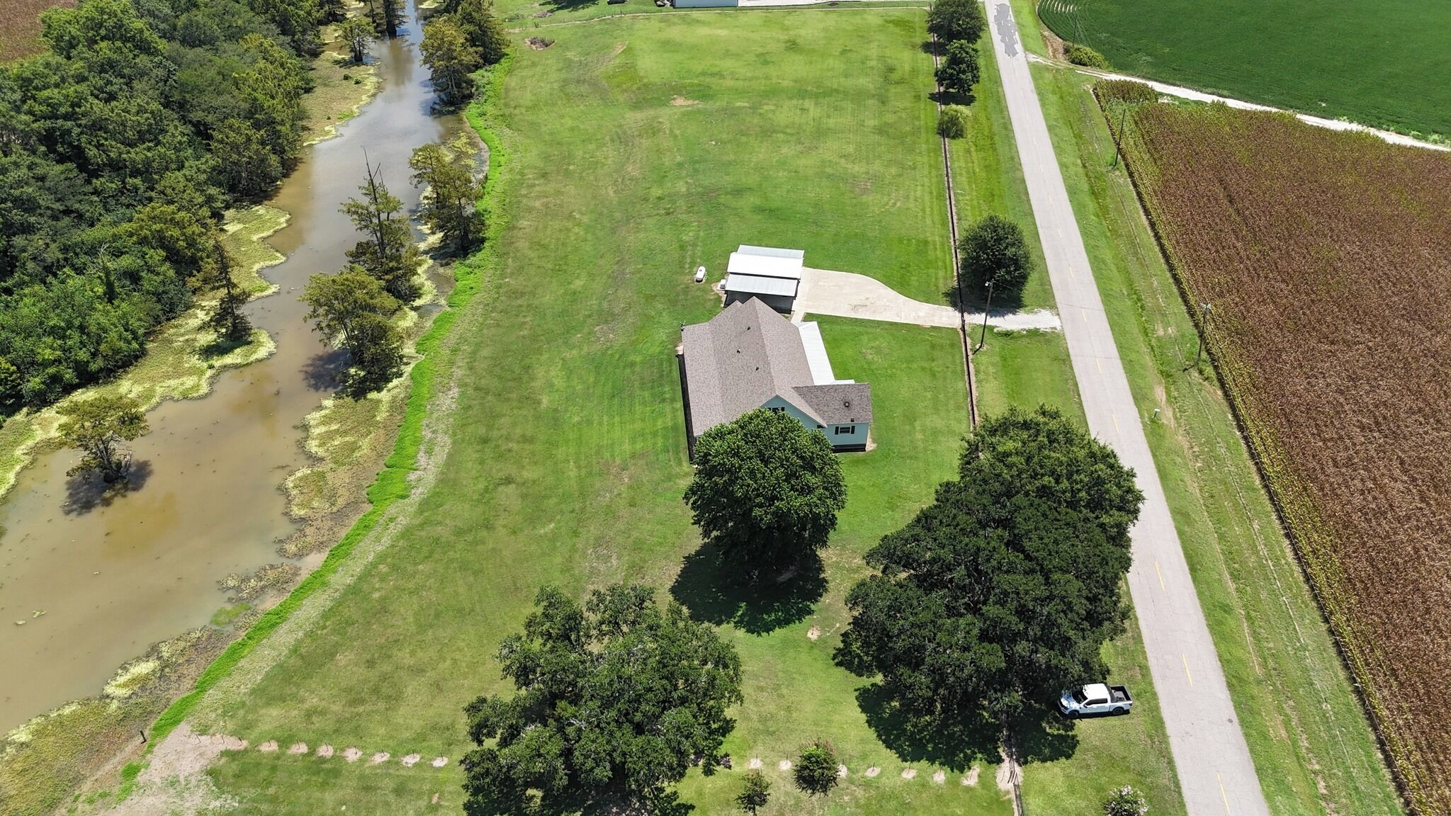 An aerial view of a property with a house, a road, and a river.