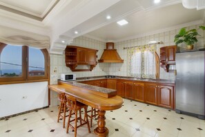 Eine K üche mit Holzausstattung, einer Arbeitsplatte aus Granit, einem Edelstahlkühlschrank und einem Fenster mit Vorhängen.