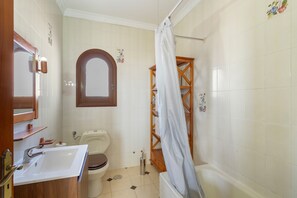 Casa de banho com lavatório, sanita e banheira.