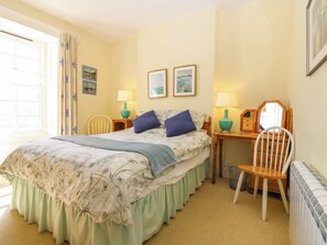 A bedroom with a bed, two bedside lamps, a chair, a desk, and a radiator. - Lightkeepers Retreat (Eyemouth)