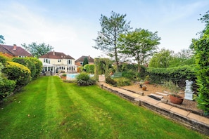 A well-maintained garden with a swimming pool, surrounded by houses.