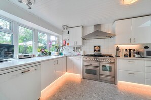 A modern kitchen with white cabinetry, a stainless steel stove, and a dishwasher.