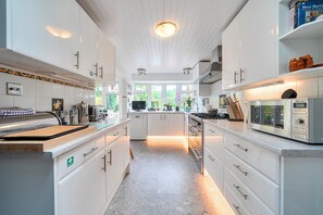 Una cocina moderna con armarios blancos, una isla central y vistas al exterior.