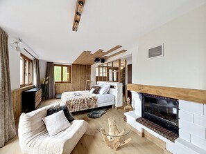 Ein Schlafzimmer mit Kamin, einer Couch, einem Bett und einem Fenster mit Vorhängen.