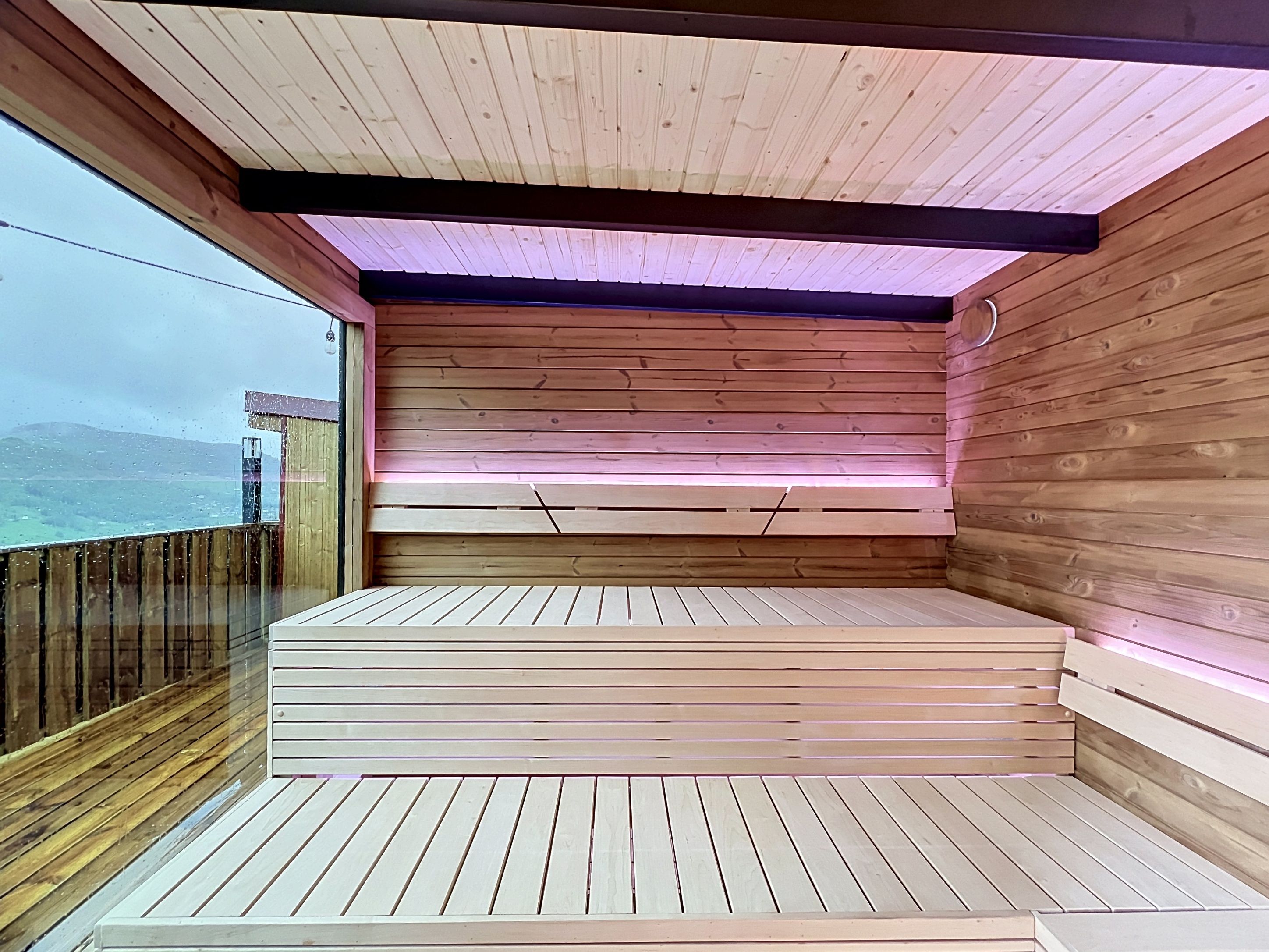 Une terrasse en bois avec un banc intégré et une vue sur la mer.