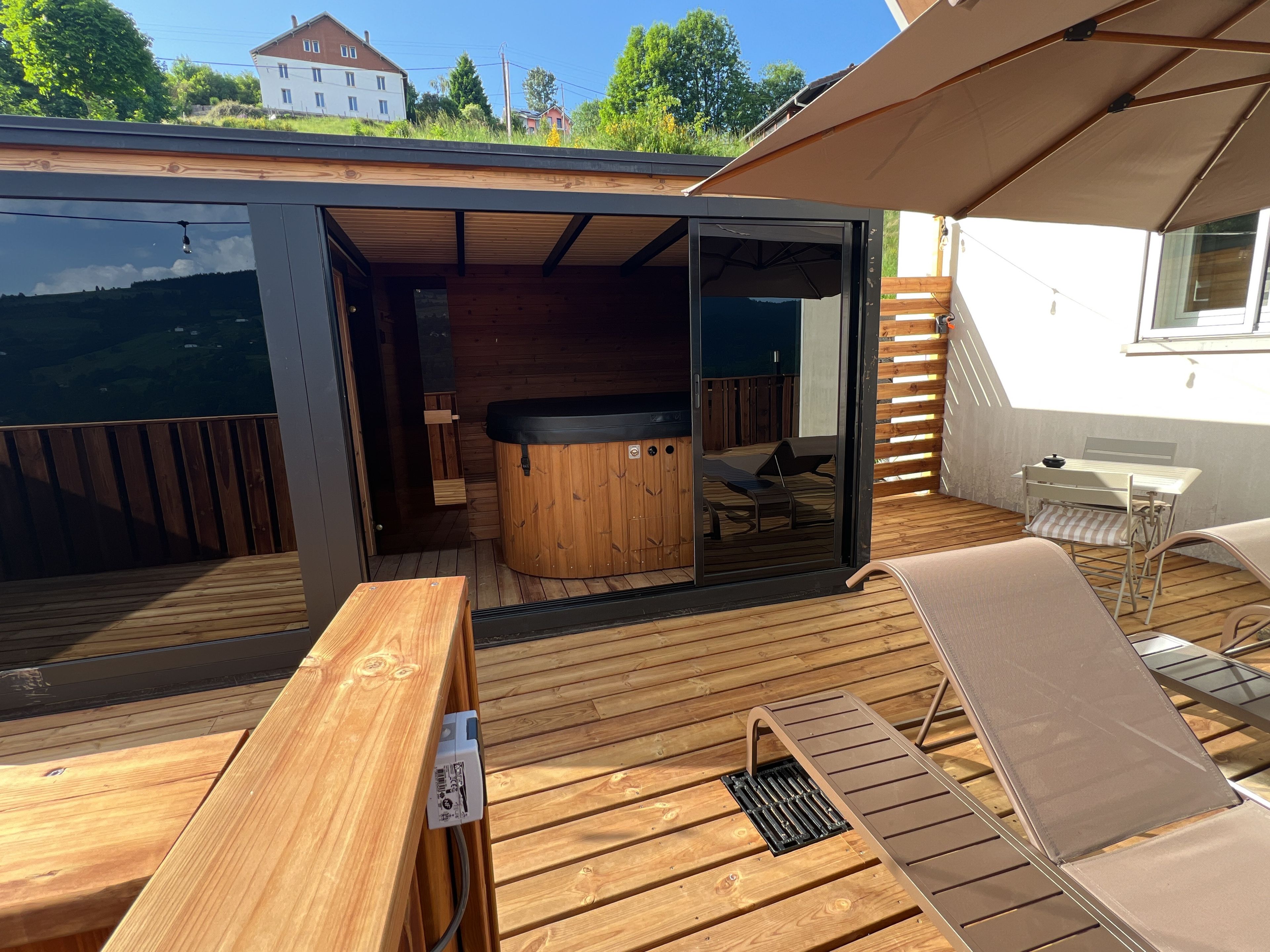 An outdoor deck with a hot tub, wooden furniture, and a table.