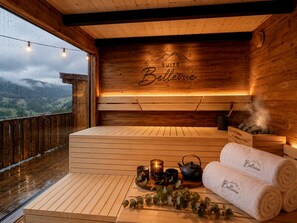 A wooden sauna suite with a view of the mountains, a wooden bench, a tea set, and towels with the word 'Bellevue' on them. - Bellevue - Private Sauna & Jacuzzi (La Bresse)