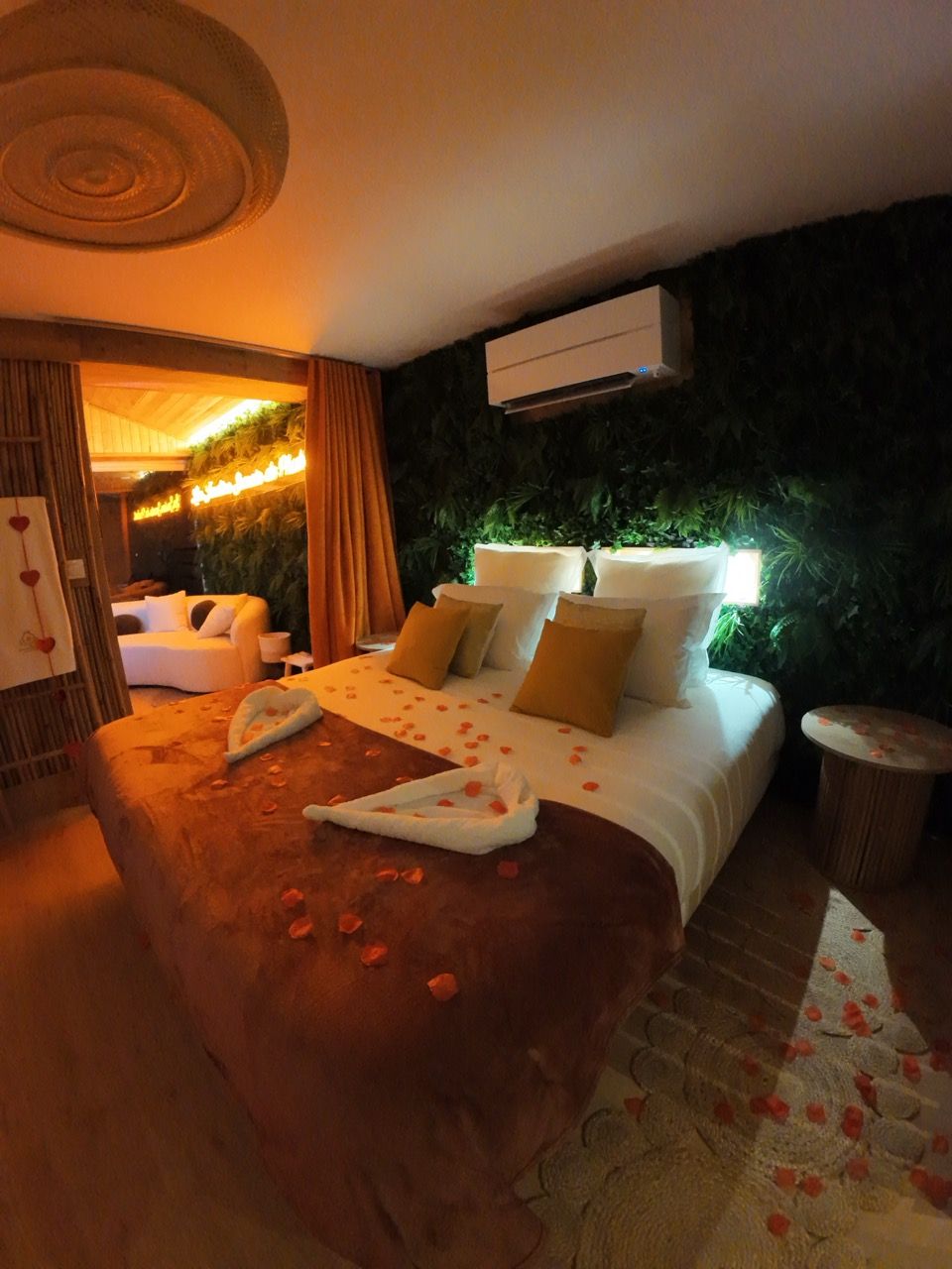Une chambre d’hôtel avec un grand lit, un coin salon avec un canapé, une petite table et un climatiseur fixé au mur.