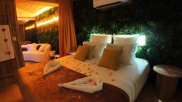 Une chambre d’hôtel avec un grand lit, un coin salon avec un canapé, une petite table et un climatiseur fixé au mur.