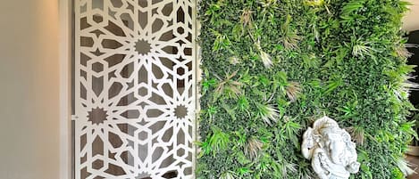 Una pared decorativa con un diseño geométrico y abundante follaje verde.