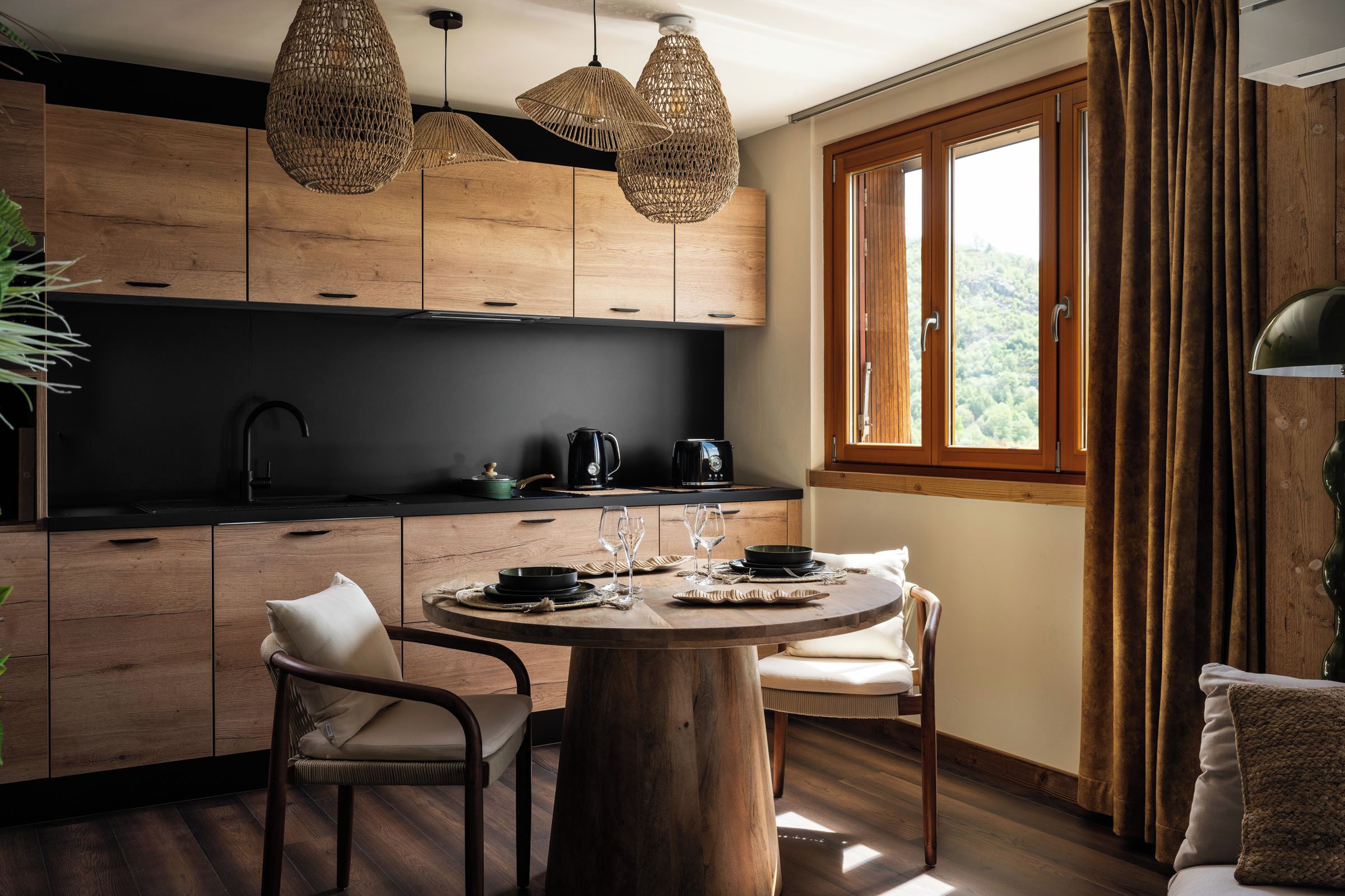 Une cuisine moderne avec des meubles en bois, une table à manger ronde et une fenêtre avec des rideaux.