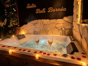 Un bain à remous rempli de pétales de rose, agrémenté de bougies et de deux coupes de champagne.