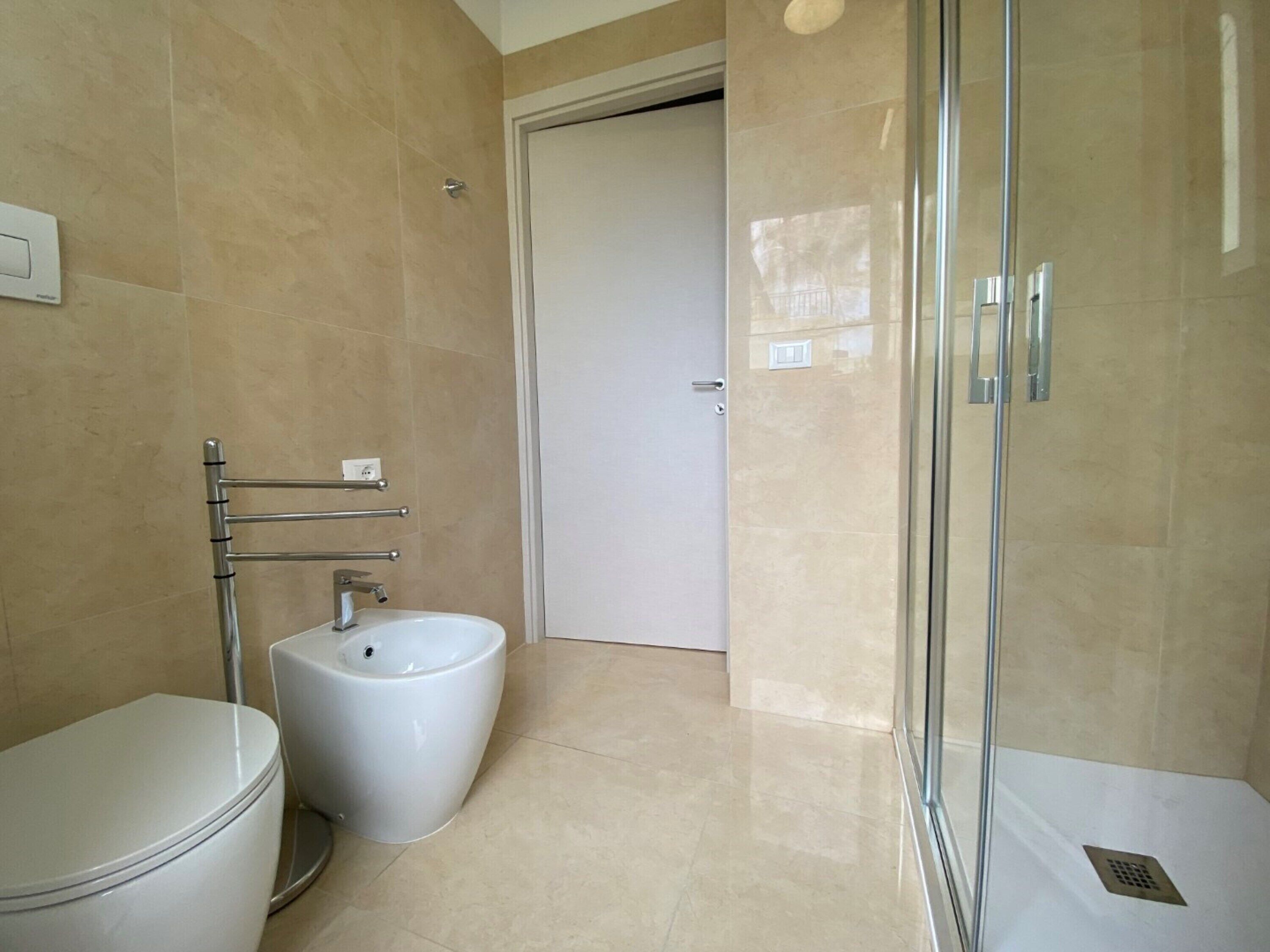 A bathroom with a toilet, bidet, and glass shower enclosure.