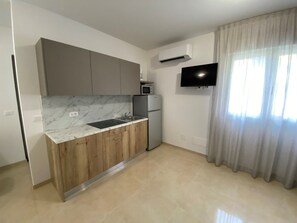 Eine moderne Küche mit Marmorarbeitsplatten, Holzschränken, einer eingebauten Mikrowelle und einem flachbildschirmfernseher an der Wand.