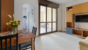 A modern living room with a dining table, chairs, a TV, and a sliding glass door leading to a balcony. - Comfortable 50m2 flat for 4 people, on the 1st floor with lift.Located in the Certosa area, a neighborhood well connected to the centre, the motorways & the exhibition centres. Nearby is the historic Certosa di Garegnano, famous for its frescoes.On foot  (Milan)