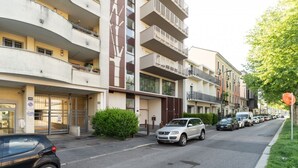 A multi-story residential building with balconies, a gated entrance, and parked cars on the street. - Comfortable 50m2 flat for 4 people, on the 1st floor with lift.Located in the Certosa area, a neighborhood well connected to the centre, the motorways & the exhibition centres. Nearby is the historic Certosa di Garegnano, famous for its frescoes.On foot  (Milan)