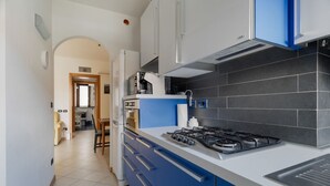 A modern kitchen with blue cabinets, a gas stove, and a black tiled backsplash. - Comfortable 50m2 flat for 4 people, on the 1st floor with lift.Located in the Certosa area, a neighborhood well connected to the centre, the motorways & the exhibition centres. Nearby is the historic Certosa di Garegnano, famous for its frescoes.On foot  (Milan)
