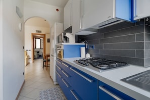 Eine moderne Küche mit blauen Schränken, einem Gasherd und einer schwarzen Küchenzeile.