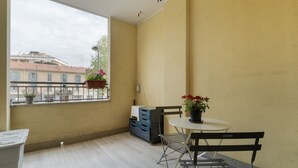 A balcony with a table, chairs, a potted plant, and a blue storage unit. - Comfortable 50m2 flat for 4 people, on the 1st floor with lift.Located in the Certosa area, a neighborhood well connected to the centre, the motorways & the exhibition centres. Nearby is the historic Certosa di Garegnano, famous for its frescoes.On foot  (Milan)