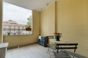Ein Balkon mit Tisch, Stühlen, einer Kübelpflanze und einem blauen Stauraum.