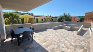 A rooftop patio with a table and chairs, a fire pit, and a view of surrounding buildings. - Modern Studio With Spectacular Private Terrace (San Michele al Tagliamento)