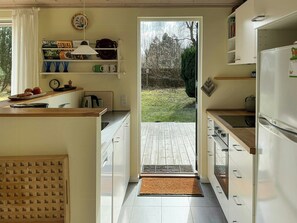 Cucina con piano di lavoro in legno, mobili bianchi e vista sul giardino.