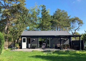 Una baita moderna con una veranda, un patio coperto e una porta che dà su un piccolo ambiente interno.