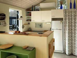 Una cucina compatta con piano di lavoro in legno, lavello integrato e frigorifero bianco.