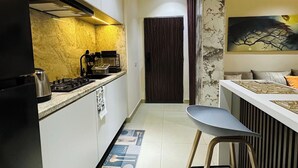 A modern kitchen with a central island, a dining area with a bar, and a dark wooden door leading to another room. - Atlas XN Apartment (Abuja)