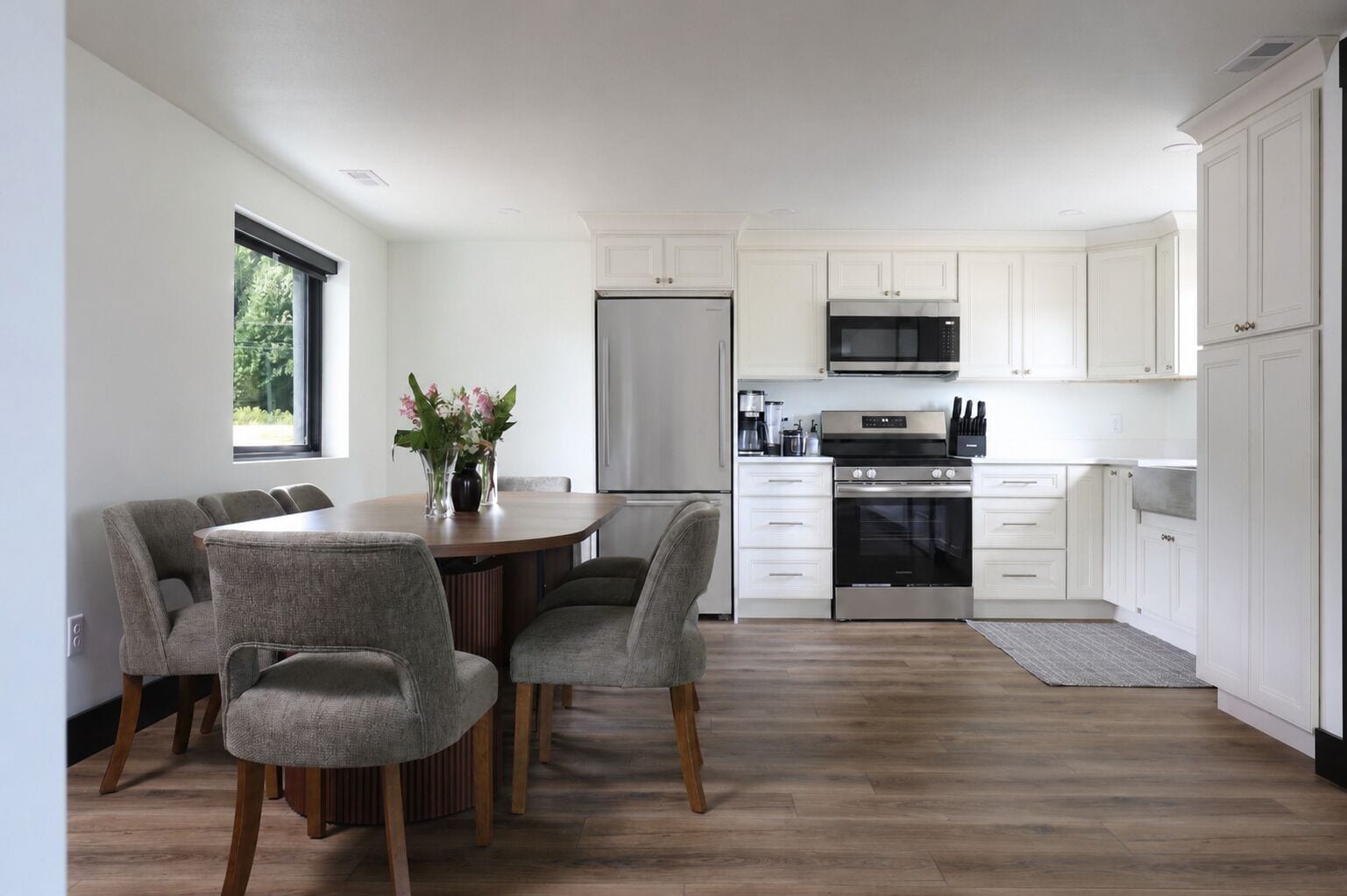 A modern kitchen with white cabinetry, a stainless steel refrigerator, a microwave, and an oven.