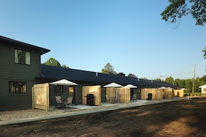 A row of cabins with outdoor seating and a barbecue area.