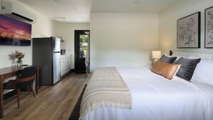 Ein Hotelzimmer mit Bett, Schreibtisch, Kühlschrank und Blick ins Freie.