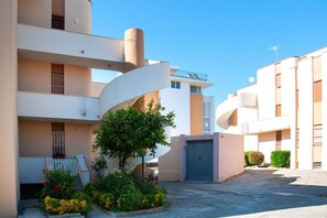 A modern building with a curved facade, a gated entrance, and a small garden area. - A cozy and comfortable 65 square meters apartment, perfect for five people, located on the first floor of a building without an elevator.The property enjoys an excellent location in Alghero, located on the street parallel to the seafront: you can reach A (Alghero)