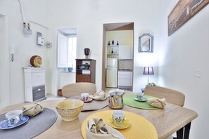 Ein Essbereich mit Tisch für zwei Personen, eine Küche im Hintergrund und ein Spiegel an der Wand.
