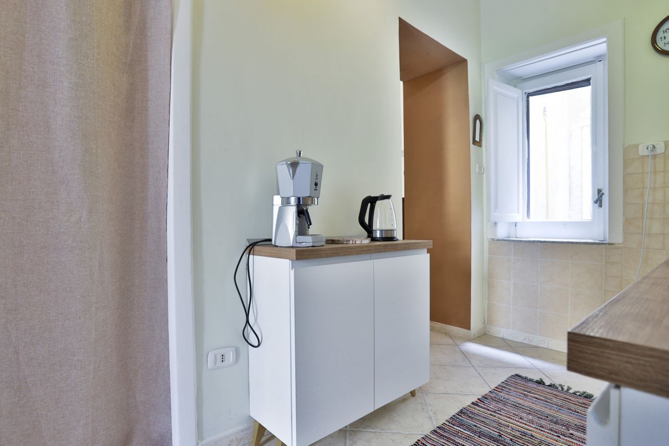 A kitchenette with a coffee maker, a kettle, and a small cabinet.