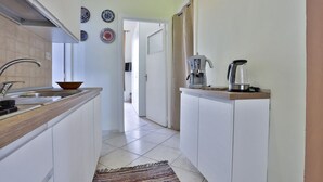 A narrow kitchen with white cabinets, a sink, and a coffee maker on the counter. - Bright and welcoming apartment for three people, located in a historic building on one of Naples' most iconic streets. The two balconies overlooking the internal courtyard ensure tranquility and privacy despite its central location. It's perfect for expl (Napoli)