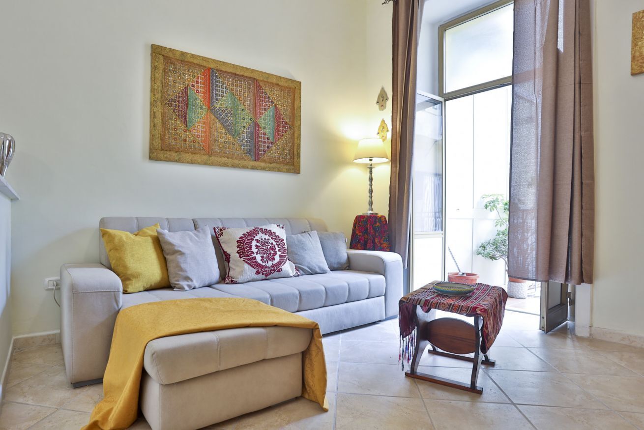 A living room with a sofa, a table, a lamp, and a large window.