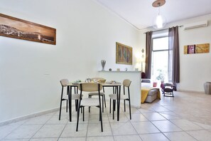 Ein Essbereich mit Tisch und Stühlen, ein Fenster mit Vorhängen und einem Bild an der Wand.