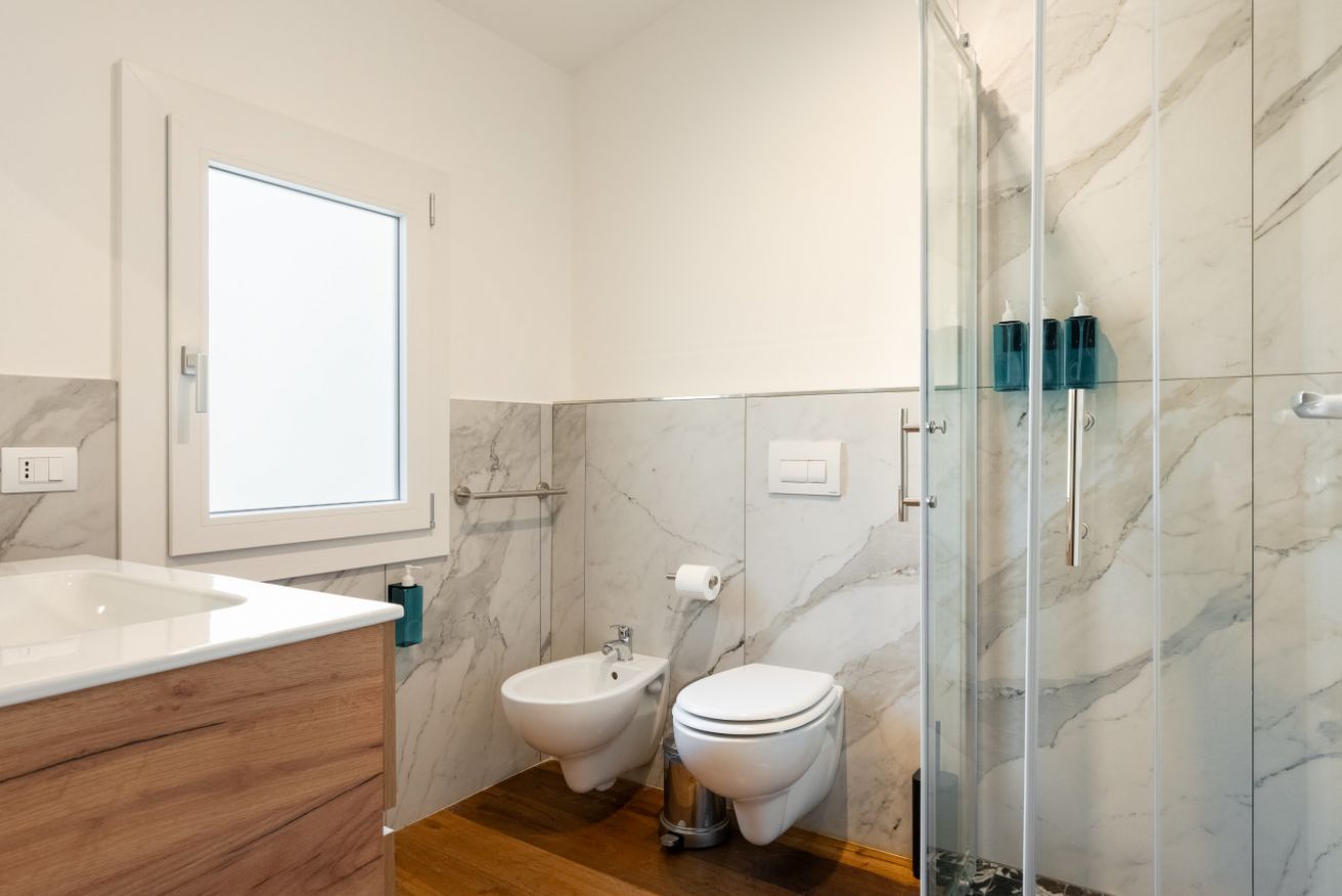 Un bagno con bidet, servizi igienici e cabina doccia in vetro.