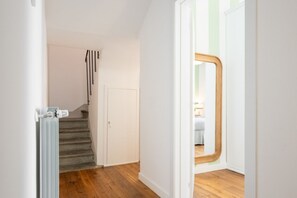 Eine Treppe führt zu einem Schlafzimmer mit Holzboden, einem Heizkörper und einer Tür mit Spiegel.
