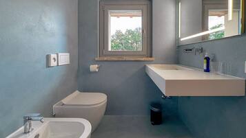 Un bagno con servizi igienici, bidet, lavandino e finestra.