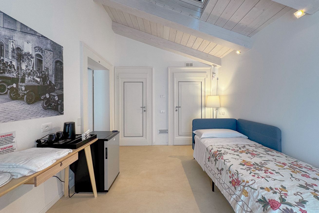A compact hotel room with a bed, desk, and a small kitchenette.