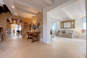 Un'ampia zona giorno con parete in mattoni, un tavolo in legno, un divano e un grande specchio.