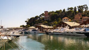 Un puerto deportivo con barcos amarrados, un edificio que parece un castillo al fondo y un cielo despejado.