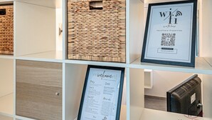 Una recepción con un cartel de bienvenida enmarcado, un letrero de Wi-Fi y un menú enmarcado.