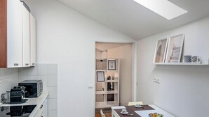 Una cocina compacta con armarios blancos, un microondas y un comedor con mesa y sillas.