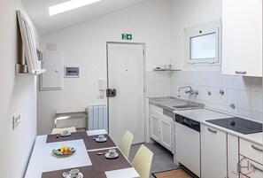 A modern kitchen with a dining area, white cabinetry, a built-in dishwasher, and a small window. - [Above the rooftops] Real Ligurian Caruggio (Varazze)