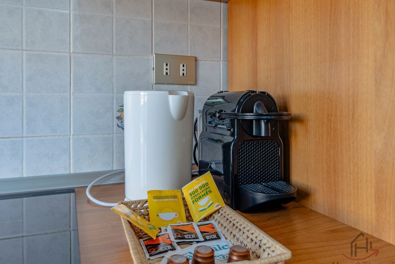 Eine Küche mit Kaffeemaschine, Wasserkocher und einer Korb mit Kaffeekapseln auf der Arbeitsfläche.