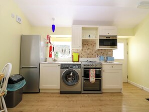 Eine kompakte Küche mit Kühlschrank aus Edelstahl, Waschmaschine, Backofen und Mikrowelle.