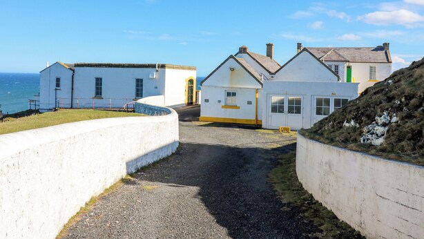 A coastal building complex with a gravel path leading to the entrance. - Lightkeepers Fold (Eyemouth)